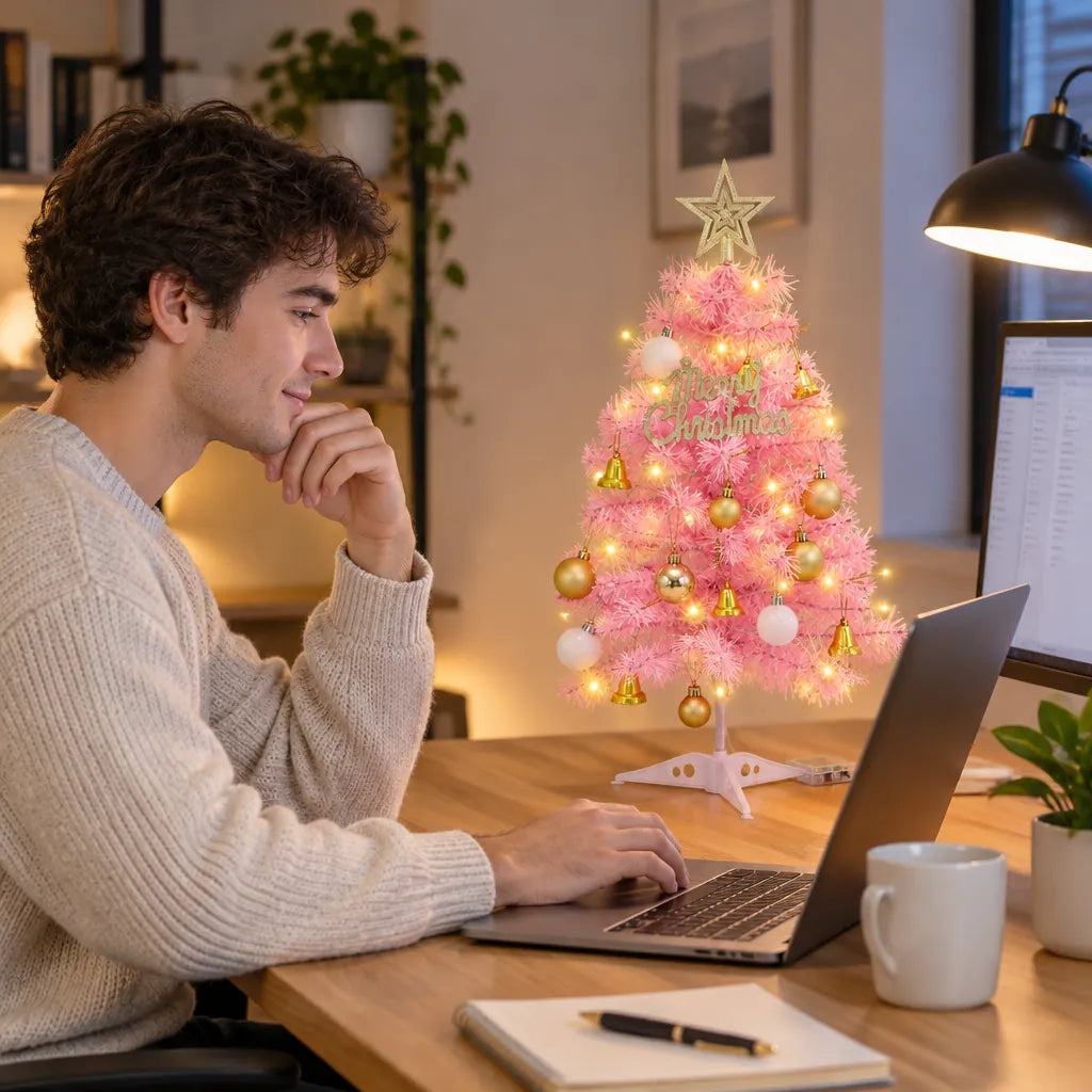 Man working at a desk next to a small pink pre-lit Christmas tree