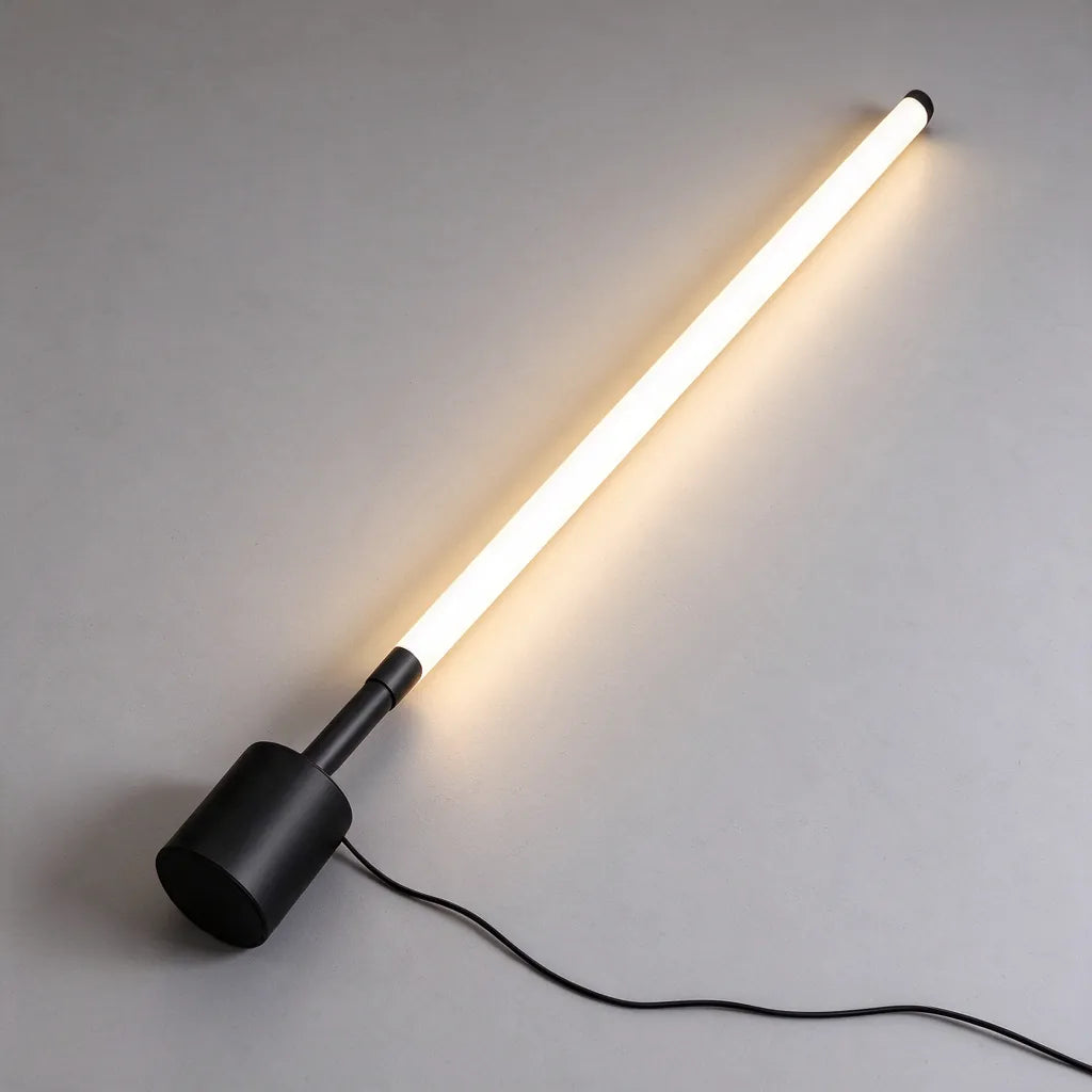 Slim black LED floor lamp laid flat with its round base and cable, a modern floor lamp for living room