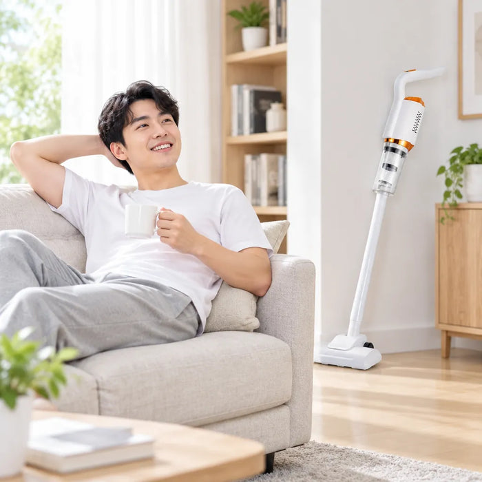 Mann entspannt mit Kaffee auf dem Sofa, der Akku-Staubsauger steht an der Wand
