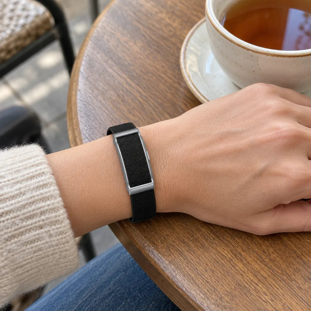 Slim fitness tracker for women on a wrist next to a cup of tea