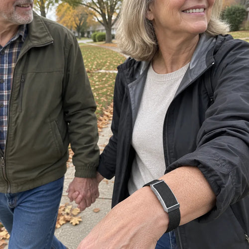 Couple in their 60s walking on a leafy street, she wears an activity tracker
