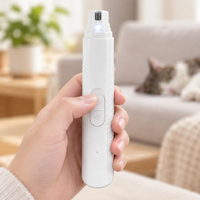 Pulgar presionando el botón de encendido de un cortaúñas eléctrico blanco para perros