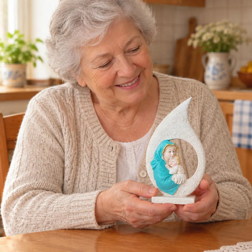 Grandmother smiling while holding a Virgin Mary figurine at the kitchen table