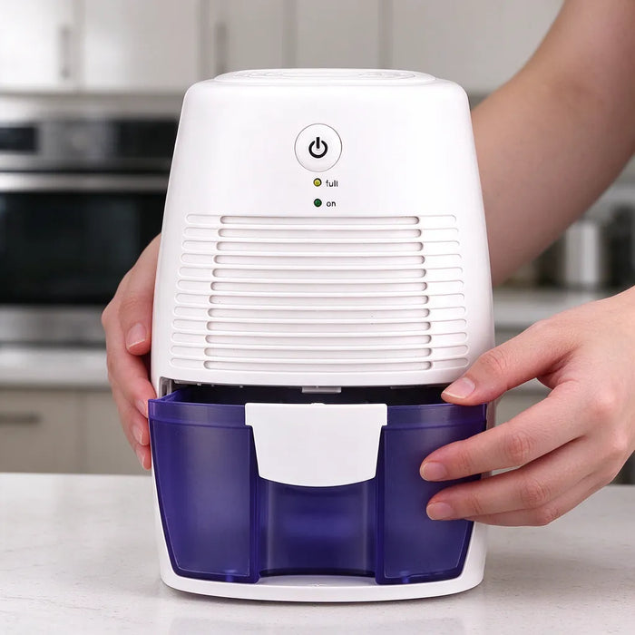 Hands sliding the water tank out of a small dehumidifier for bedrooms