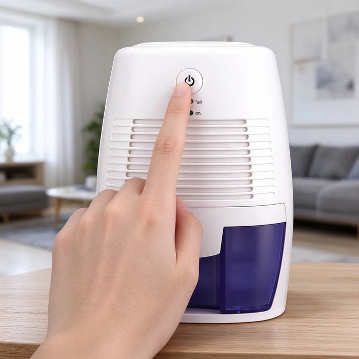Finger pressing the power button on a portable mini dehumidifier