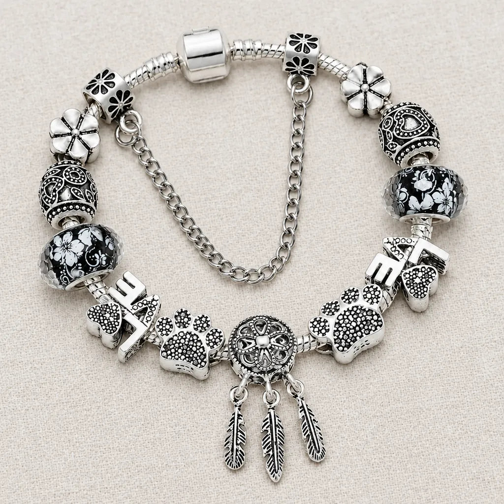 Single silver charm bracelet with charms for women laid on a light linen surface
