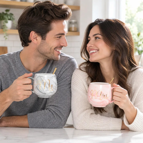 Smiling couple holding his and hers marble mugs, Mr and Mrs, at the kitchen counter
