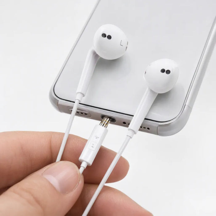 Mano conectando audifonos blancos con cable a un celular