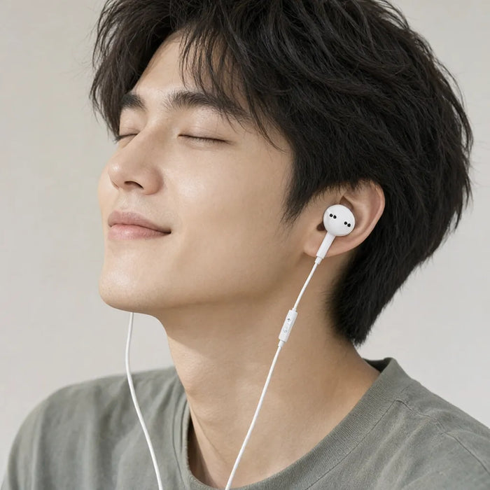 Hombre sonriendo con los ojos cerrados escuchando musica con audifonos con cable