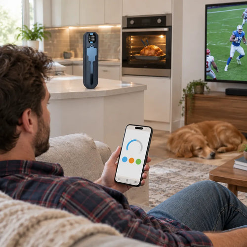 Mann auf dem Sofa schaut Fussball, die App des Ofenthermometers zeigt die Temperatur