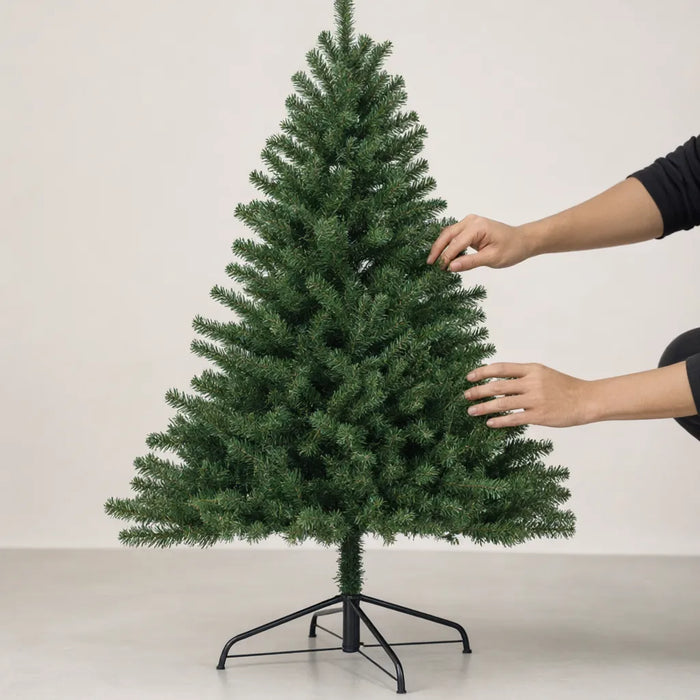 Hands spreading the needle branches of a green artificial Christmas tree to make it look full