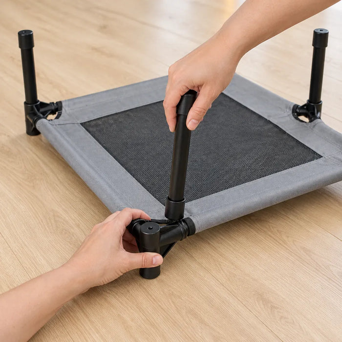 Hands pushing a leg into the corner connector of a dog cot
