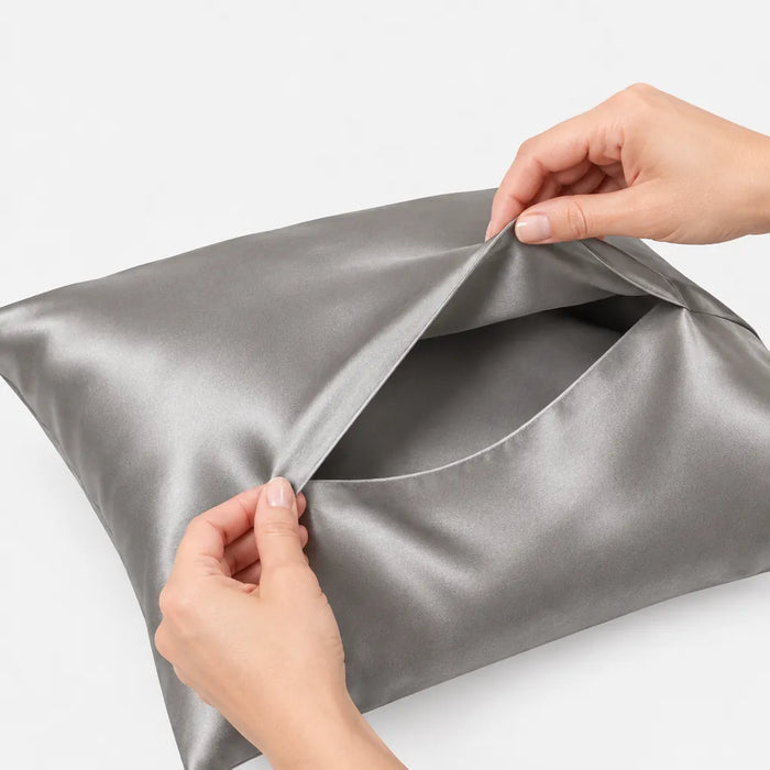 Hands lifting the envelope flap of a grey satin pillowcase