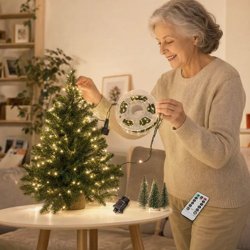Ältere Frau hängt eine warmweisse LED-Lichterkette an einen kleinen Tischweihnachtsbaum