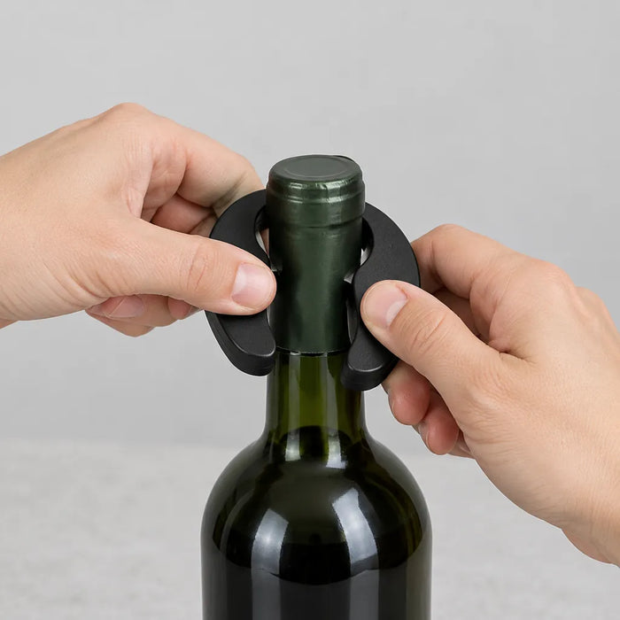 Hands cutting the foil off a wine bottle with the black foil cutter