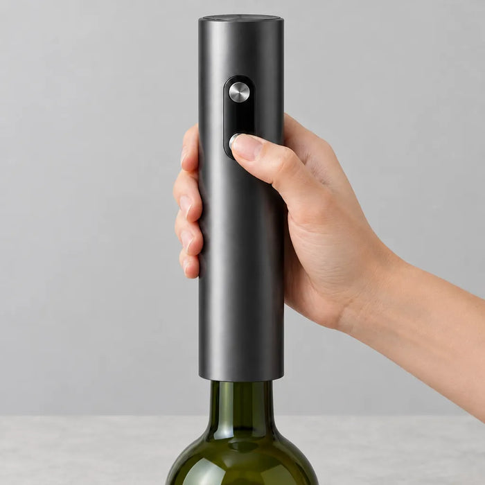 Electric corkscrew held upright on a wine bottle, thumb on the lower button