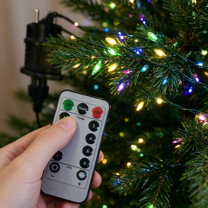 Mano presionando el botón de encendido del control de las luces del árbol de Navidad