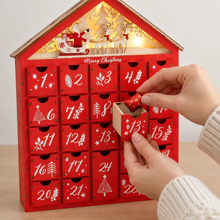 Manos poniendo un chocolate envuelto en un cajón del calendario de adviento de madera