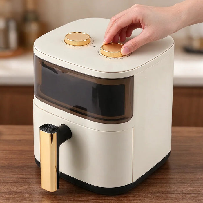 Hand turning the gold temperature dial on top of a large air fryer