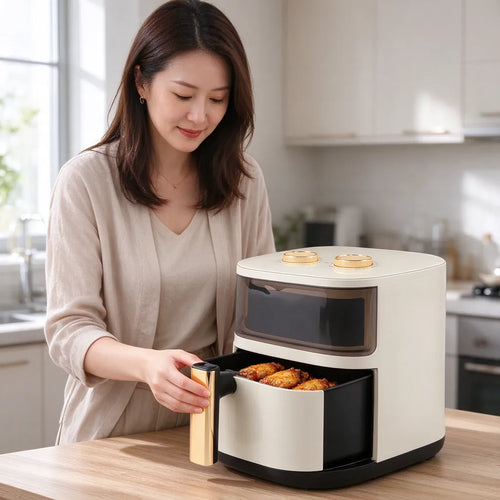 Woman taking chicken wings out of a cream white large air fryer in a bright kitchen