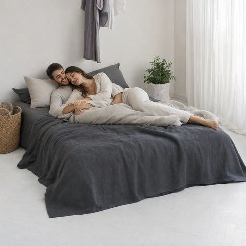 Couple relaxing on a bed with a charcoal grey linen sheet