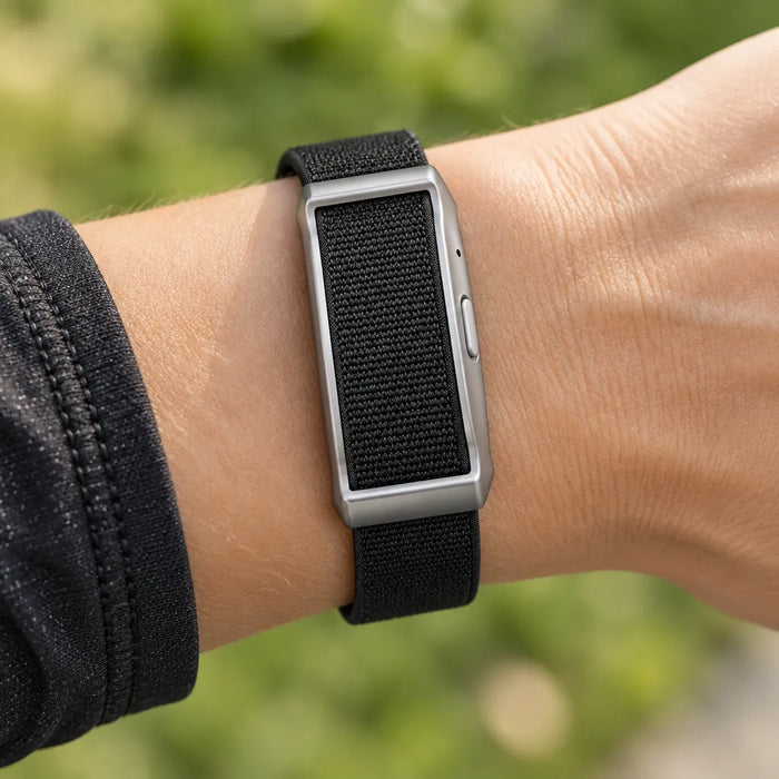 Runner's wrist wearing a black and silver screenless fitness tracker band during a run in the park