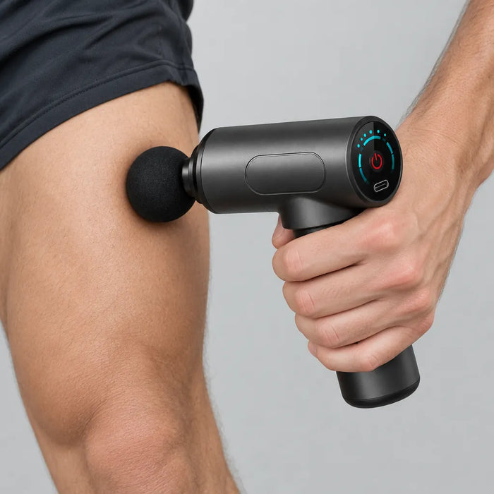 Hand pressing the ball head of a mini massage gun on the thigh muscle after a workout
