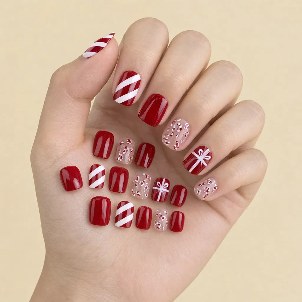 Hand wearing red christmas press on nails with candy cane stripe, gift bow and plain red designs